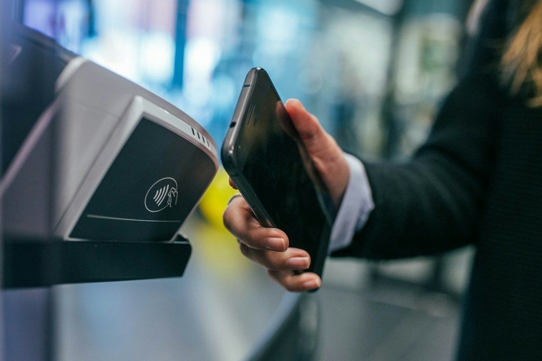 Smartphone wird an ein kontaktloses Lesegerät für eine Zahlung gehalten